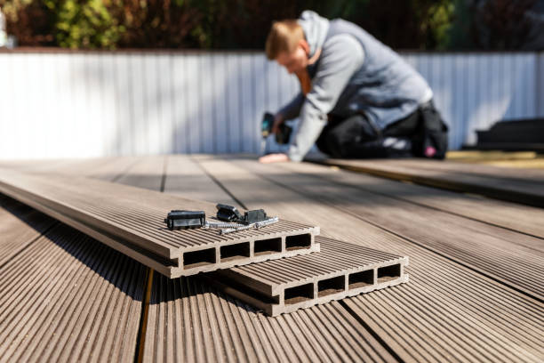 Wood Deck Builder in Redmond, WA measuring deck framing beside a sloped backyard patio